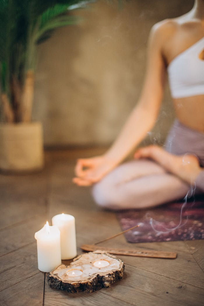 about-01 Woman practicing meditation in lotus pose with candles and incense, focusing on wellness and relaxation.