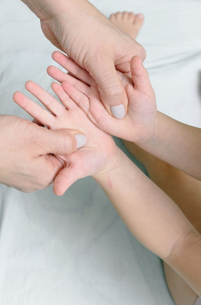 Close-up of an adult giving a gentle massage to a child's hand.