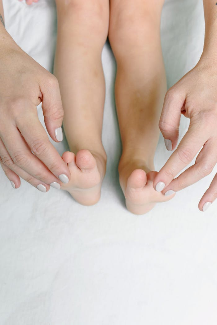 Close-up of hands massaging a child's feet, emphasizing care and relaxation.